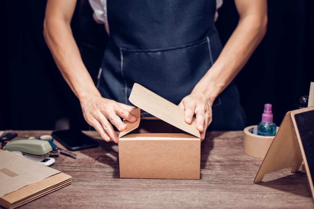 Persona diseñando una caja a medida sobre un plano, representando la personalización.